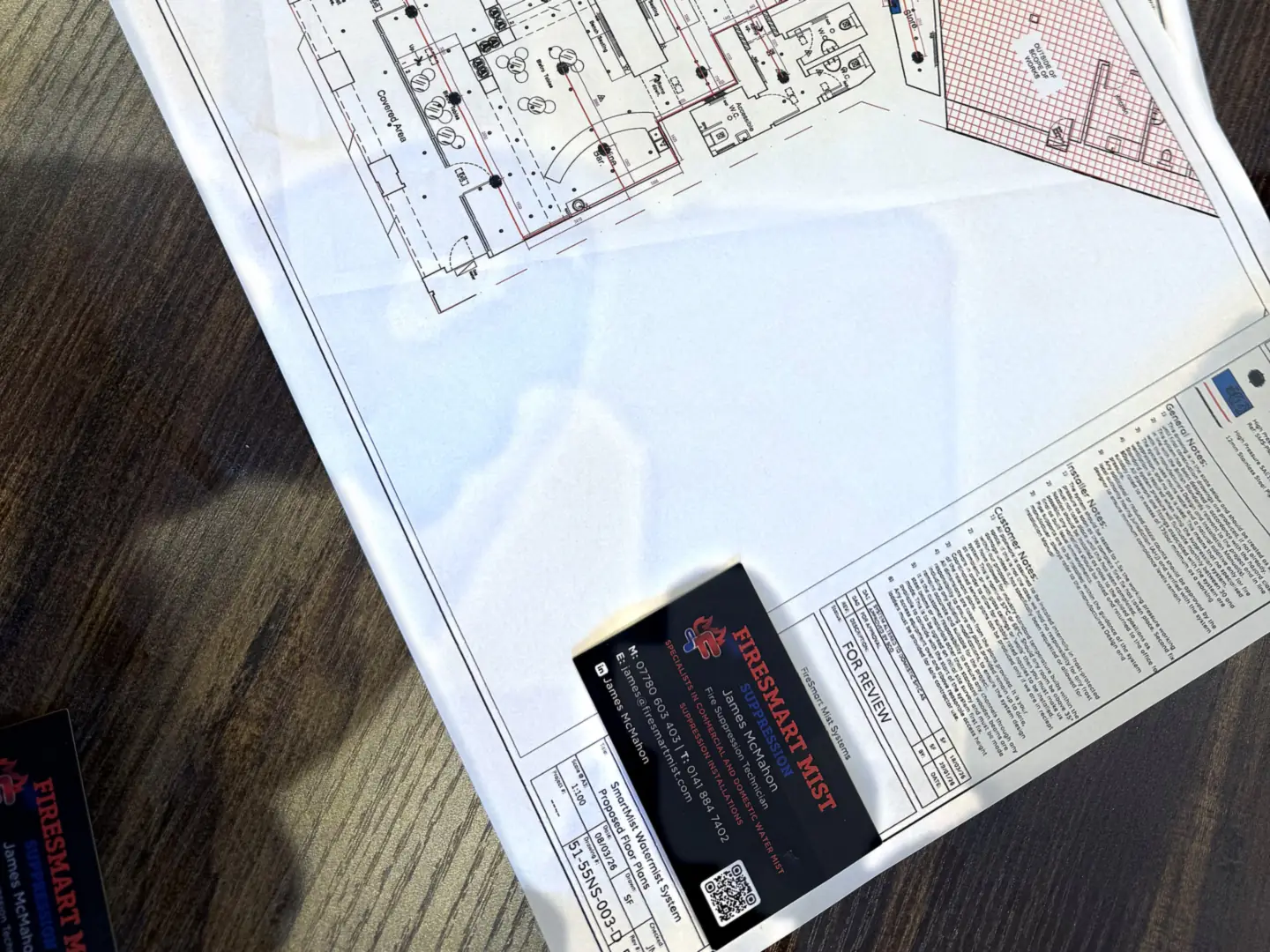 Water mist system floor plans with nozzle positions marked, on a desk with a Firesmart Mist business card