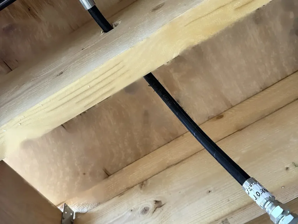 Flexible water mist feed hose run between timber joists