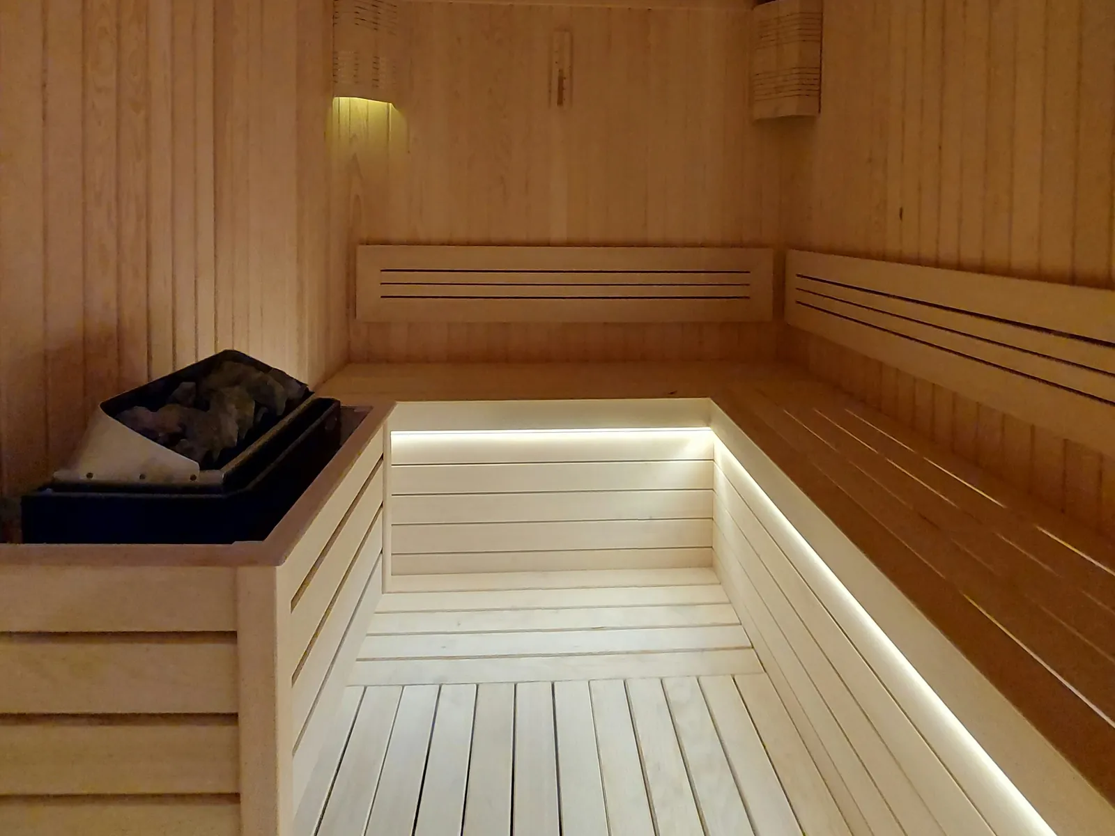 Timber commercial sauna with tiered benches and a heater